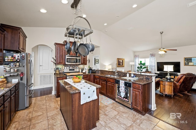 kitchen featuring ceiling fan, a center island, vaulted ceiling, decorative backsplash, and appliances with stainless steel finishes