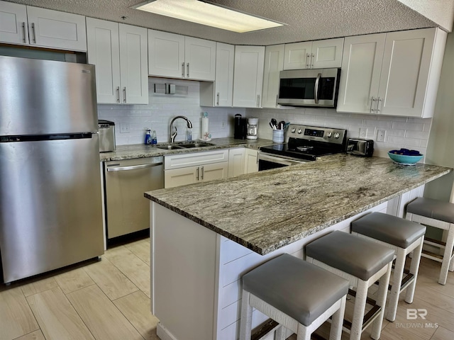 kitchen with appliances with stainless steel finishes, a breakfast bar, sink, and kitchen peninsula