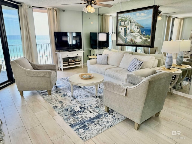 living room with floor to ceiling windows, ceiling fan, and a textured ceiling