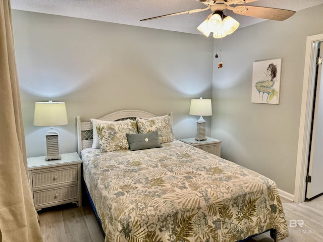 bedroom with ceiling fan, light hardwood / wood-style flooring, and a textured ceiling