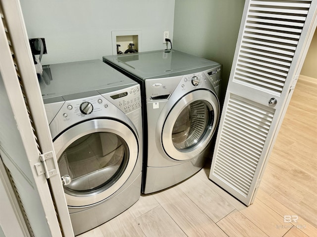 washroom with washer and dryer and light hardwood / wood-style flooring