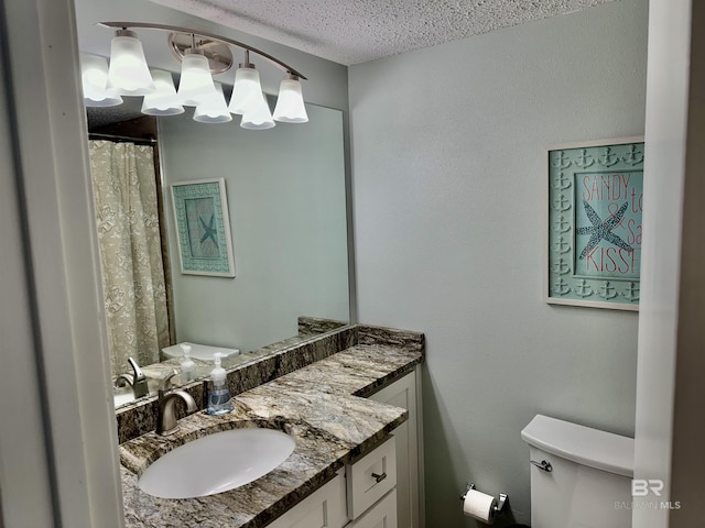 bathroom with vanity, toilet, and a textured ceiling