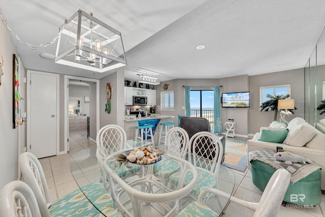 tiled dining space featuring a textured ceiling and a notable chandelier