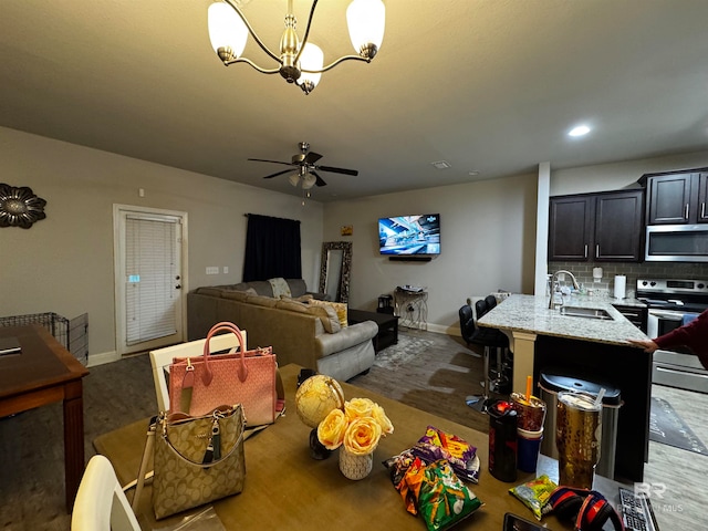 dining space featuring ceiling fan with notable chandelier and sink