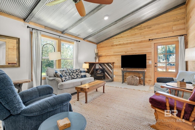 living room with a wealth of natural light, wood walls, ceiling fan, and high vaulted ceiling