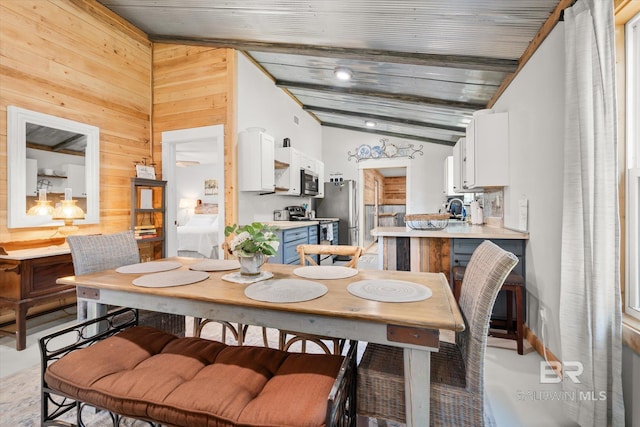 dining area featuring vaulted ceiling with beams, wood walls, and wooden ceiling