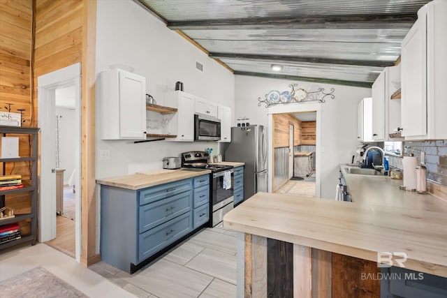 kitchen with stainless steel appliances, blue cabinets, sink, lofted ceiling with beams, and white cabinets