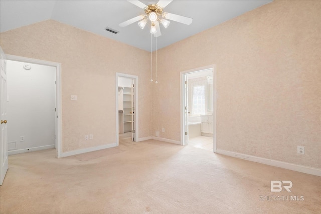 unfurnished bedroom with light carpet, a walk in closet, visible vents, and lofted ceiling