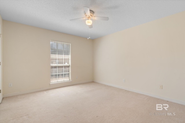 carpeted spare room featuring a textured ceiling, ceiling fan, and baseboards