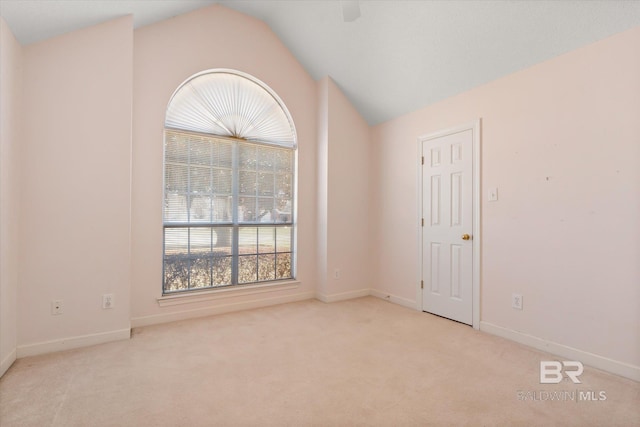 carpeted empty room with lofted ceiling and baseboards