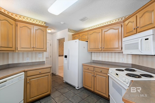 kitchen with white appliances, wallpapered walls, visible vents, dark tile patterned flooring, and a textured ceiling