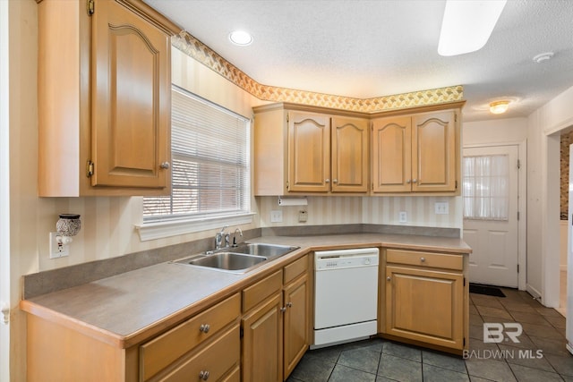 kitchen with a textured ceiling, dark tile patterned floors, white dishwasher, and a sink