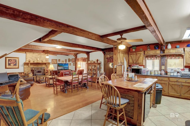 kitchen with beamed ceiling, a breakfast bar, light tile patterned floors, and ceiling fan