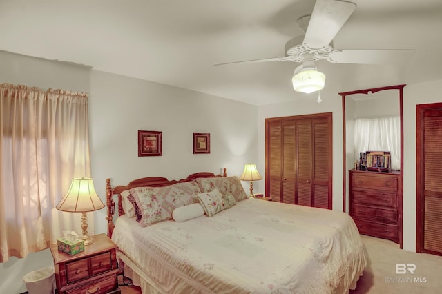 bedroom with two closets, light colored carpet, and ceiling fan