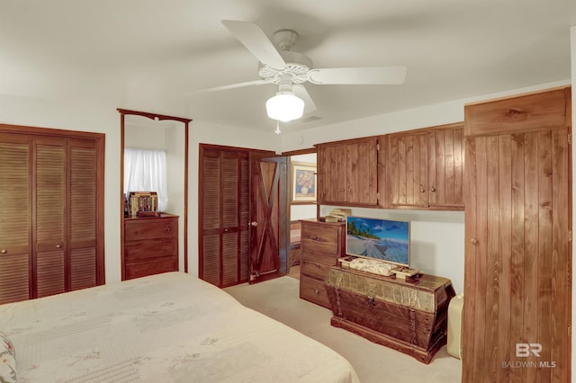 carpeted bedroom featuring ceiling fan and multiple closets