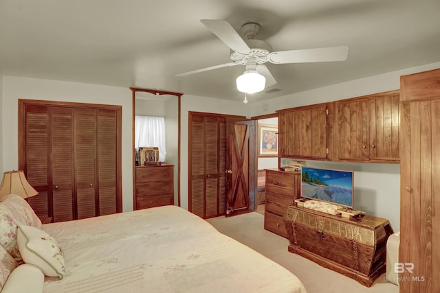 bedroom featuring multiple closets, ceiling fan, and light carpet