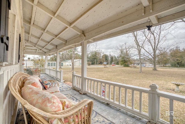 wooden terrace featuring a yard and covered porch