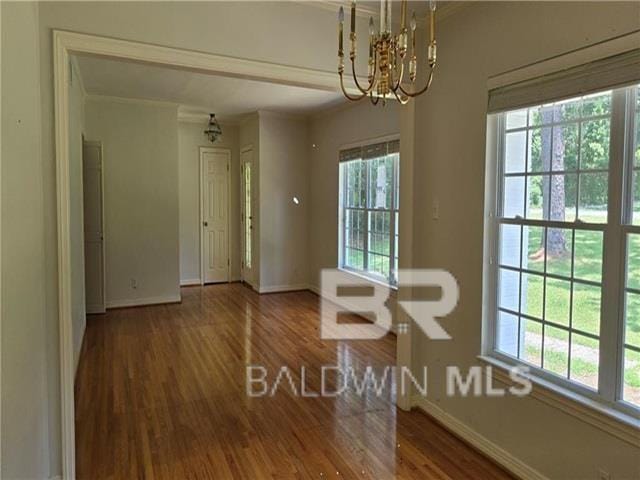 unfurnished dining area featuring an inviting chandelier, dark hardwood / wood-style floors, and a healthy amount of sunlight