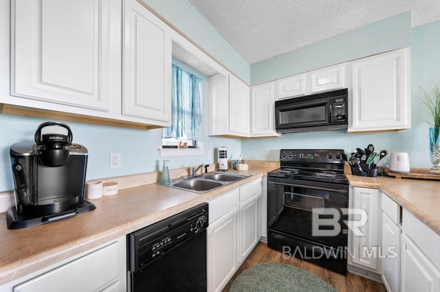 kitchen featuring black appliances, a sink, a textured ceiling, white cabinets, and light countertops