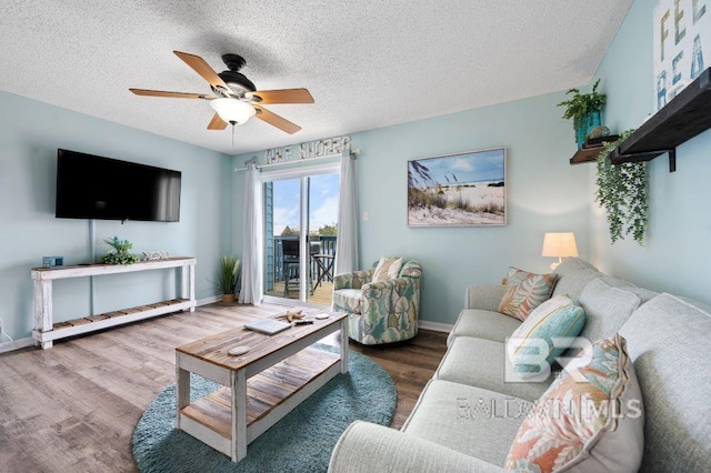 living room with a textured ceiling, wood finished floors, baseboards, and ceiling fan