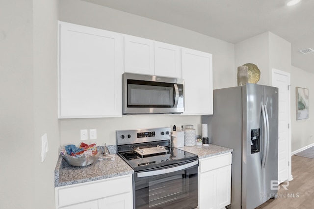 24926 Ponder Loop, Loxley, AL 36551 - kitchen featuring appliances with stainless steel finishes, white cabinets, light wood finished floors, and light stone countertops