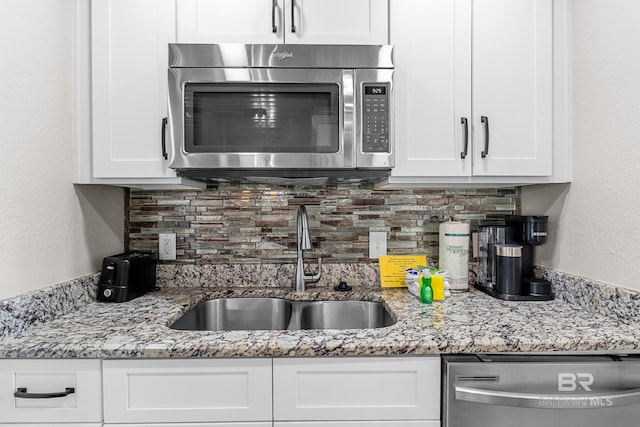 511 E Beach Blvd Unit 203, Gulf Shores, AL 36542 - kitchen with decorative backsplash, appliances with stainless steel finishes, white cabinetry, and a sink