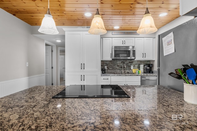 kitchen featuring decorative light fixtures, dark stone countertops, white cabinetry, and appliances with stainless steel finishes