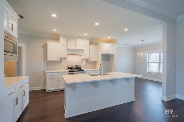 kitchen with stainless steel appliances, sink, dark hardwood / wood-style floors, white cabinetry, and an island with sink