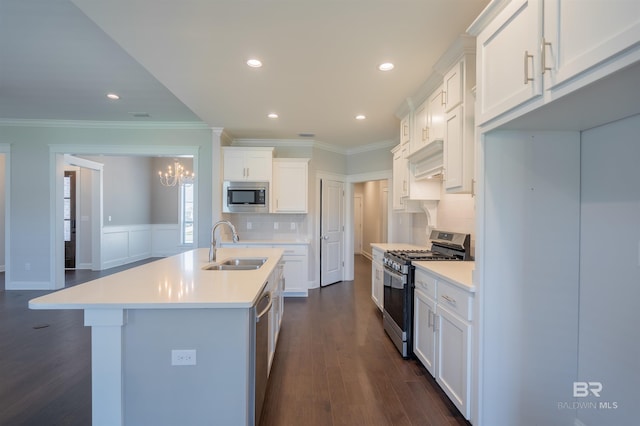 kitchen featuring appliances with stainless steel finishes, backsplash, sink, a center island with sink, and white cabinetry