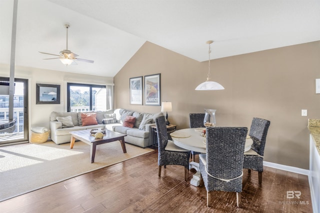 dining area with ceiling fan, vaulted ceiling, baseboards, and wood finished floors