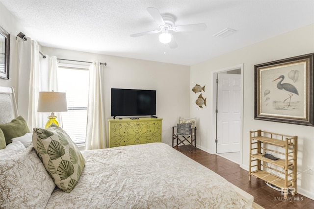 bedroom with baseboards, visible vents, a ceiling fan, dark wood-type flooring, and a textured ceiling