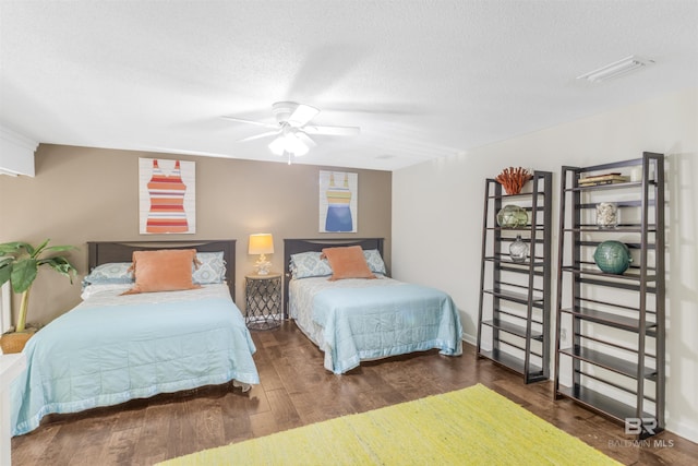 bedroom with a ceiling fan, a textured ceiling, visible vents, and wood finished floors