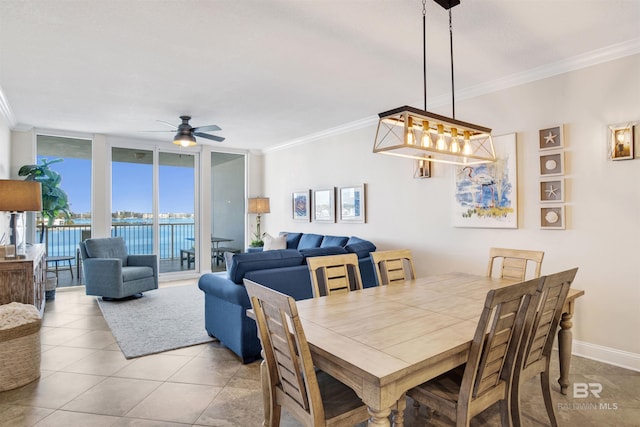 tiled dining space with a wall of windows, crown molding, baseboards, and ceiling fan