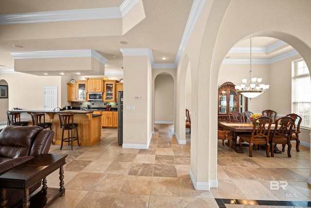 270 Cypress Lake Dr, Gulf Shores, AL 36542 - living area featuring arched walkways, ornamental molding, a tray ceiling, a chandelier, and stone tile floors