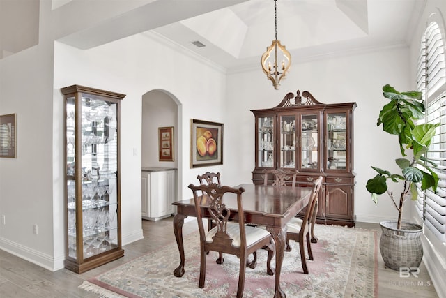 dining room with crown molding, a tray ceiling, a chandelier, and hardwood / wood-style flooring