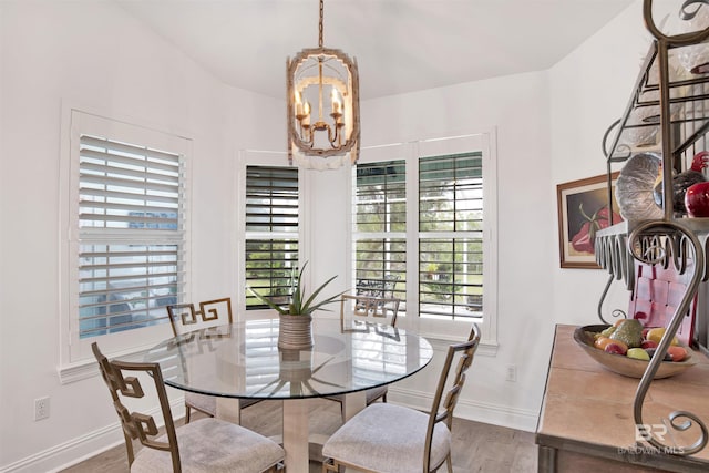 dining space with hardwood / wood-style floors, a wealth of natural light, and a notable chandelier