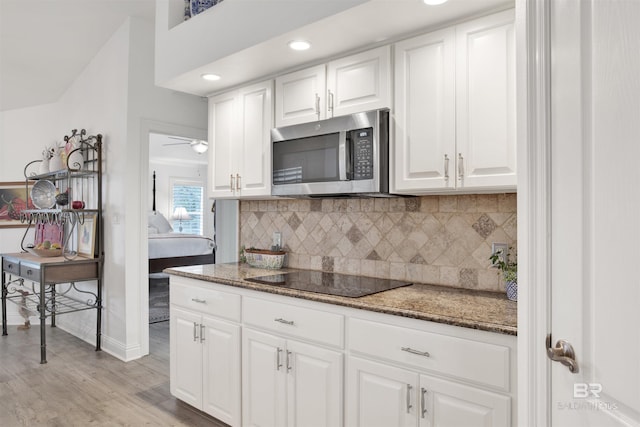 kitchen featuring white cabinetry, black electric stovetop, and dark stone counters