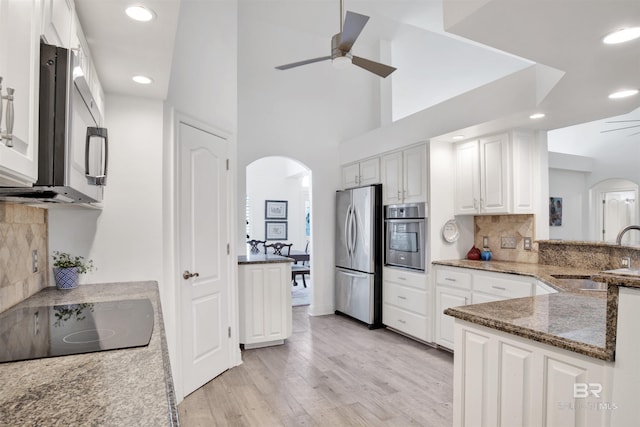 kitchen featuring sink, ceiling fan, appliances with stainless steel finishes, white cabinetry, and dark stone counters