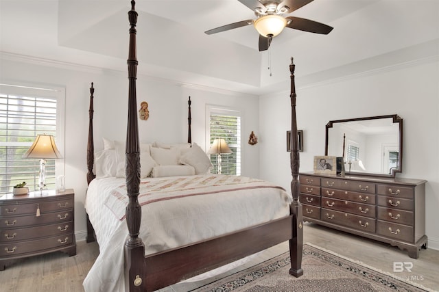 bedroom with ornamental molding, hardwood / wood-style floors, ceiling fan, and a tray ceiling