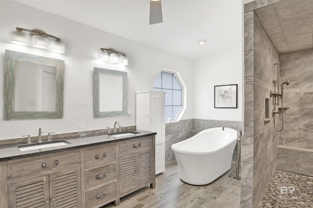 bathroom with separate shower and tub, tile walls, vanity, ceiling fan, and hardwood / wood-style floors