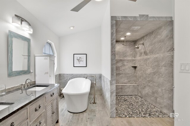 bathroom featuring ceiling fan, vanity, independent shower and bath, and tile walls