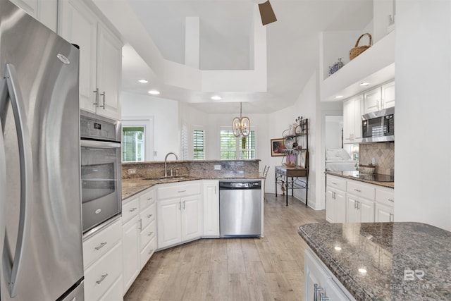 kitchen featuring white cabinetry, stainless steel appliances, tasteful backsplash, and dark stone counters