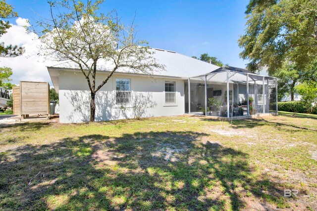 rear view of property featuring a yard and glass enclosure