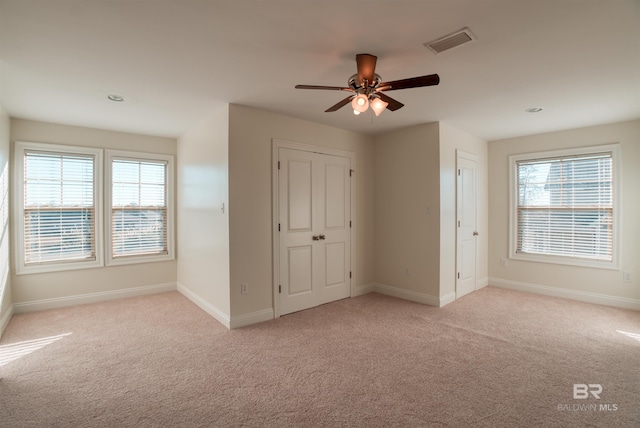 unfurnished bedroom with ceiling fan, multiple windows, and light carpet