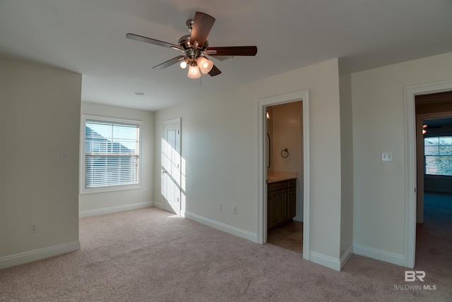 interior space with light carpet, connected bathroom, and ceiling fan