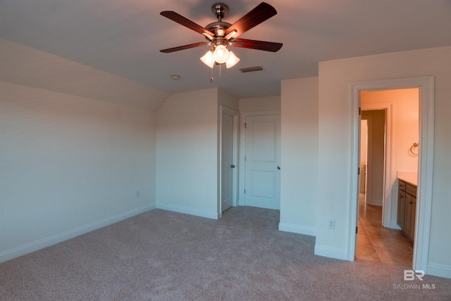 unfurnished bedroom with vaulted ceiling, light colored carpet, and ceiling fan