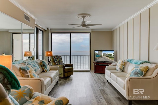 living room with crown molding, expansive windows, a water view, hardwood / wood-style floors, and ceiling fan