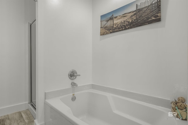 bathroom featuring hardwood / wood-style flooring and a relaxing tiled tub