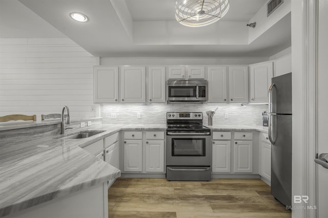 kitchen featuring appliances with stainless steel finishes, light hardwood / wood-style floors, white cabinets, and sink