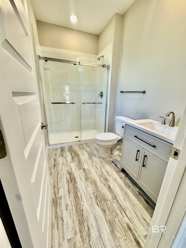 bathroom featuring hardwood / wood-style flooring, vanity, toilet, and walk in shower